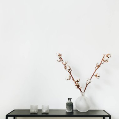 Modern İskandinav iç tasarım konsepti. Vazo, pamuk dalında ile şık raf mumlar beyaz arka plan.