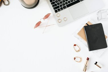 Dizüstü bilgisayar, ruj, güneş gözlüğü, beyaz arka plan aksesuarları ile Kadınsı modern ev ofis masası çalışma alanı. Düz yatıyordu, üstten bak. Moda blog, sosyal medya, web sitesi minimal kompozisyon. Kız patron kavramı.