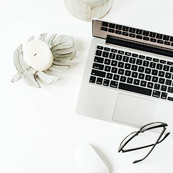 Minimal home office desk workspace with laptop, glasses on white background. Flat lay, top view.