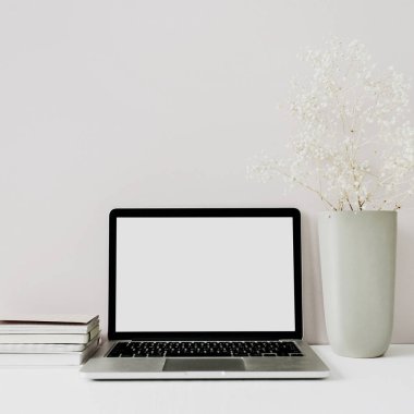 Dizüstü bilgisayar ile minimalist ev ofis masası çalışma alanı, pembe arka plan üzerinde çiçek buketi. Boş kopyalama alanı olan ön görünüm kahraman üstbilgisi.