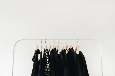 Minimal moda giysi konsepti. Siyah kadın bluz ve beyaz arka plan üzerinde askı üzerinde t-shirt.