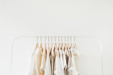 Askıda kadınsı kıyafetler var. Beyaz arka planda minimal moda kompozisyonu.