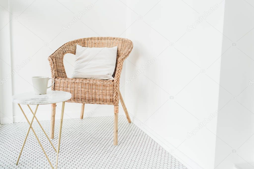 Rattan chair with pillow and marble coffee table at loggia with mosaic floor. Minimal modern Scandinavian nordic interior design concept.