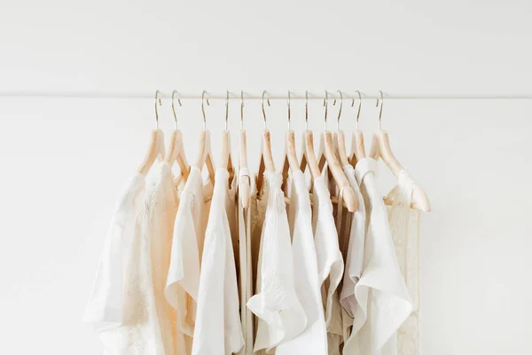 Minimal fashion clothes concept. White female blouses and t-shirts on hanger on white background.