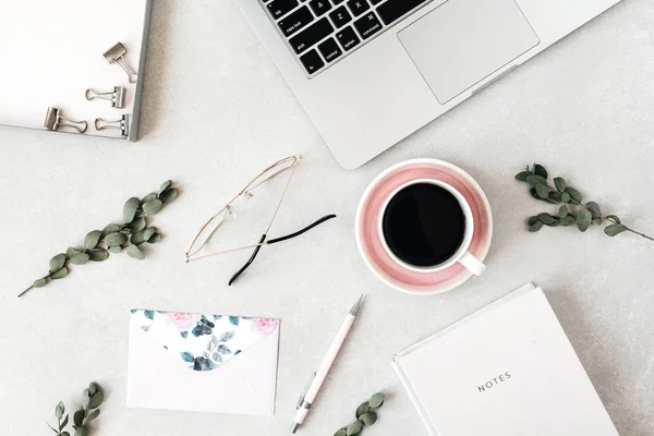 Minimal home office desk workspace with laptop, coffee, notebook, eucalyptus, envelope. Flat lay, top view social media hero header background.