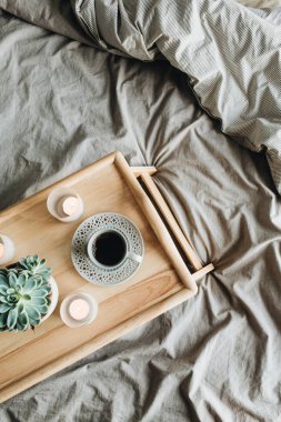 Yatakta kahve ile sabah kahvaltısı. Düz yatıyordu, üst görünüm yaşam tarzı natürmort kompozisyon. Ahşap tepsi ve gri keten.