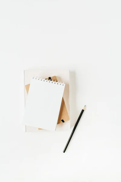 Neutral minimal office desk workspace with notebook on white background. Flat lay, top view.