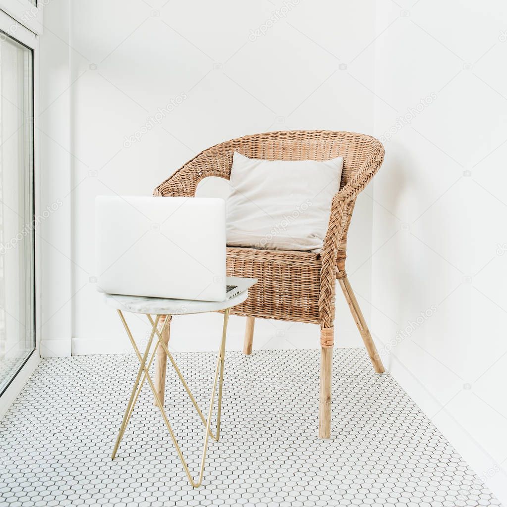 Work at home concept with laptop, rattan chair with pillow and marble coffee table at balcony with mosaic floor. Minimal modern Scandinavian nordic interior design. girl boss blog concept.