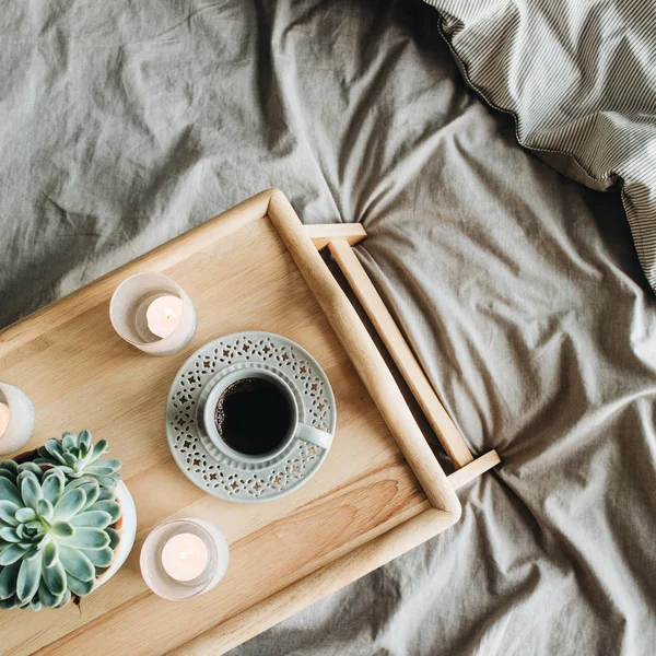 Morning breakfast with coffee in bed. Flat lay, top view lifestyle still life composition. Wooden tray and grey linen.