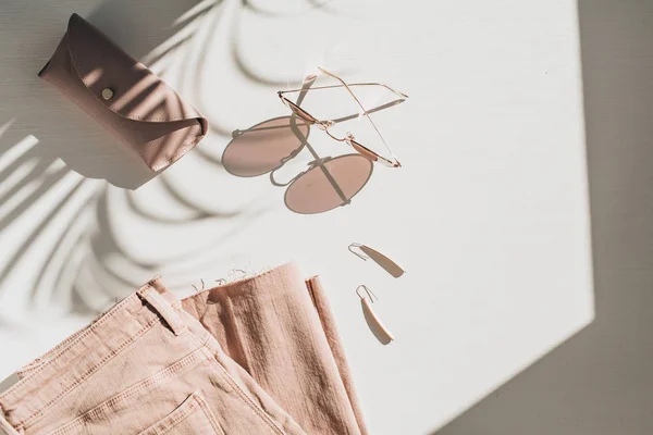 白い背景に女性の服やアクセサリーとファッション構成 白い背景にイヤリング サングラス ピンクのジーンズキュロット フラットレイ トップビューライフスタイルブログコンセプト — ストック写真