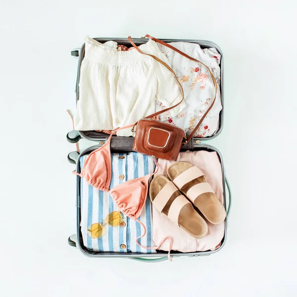 手提行李 比基尼 太阳镜 复古相机和白色背景的衣服 顶视图旅游度假时尚组合 — 图库照片
