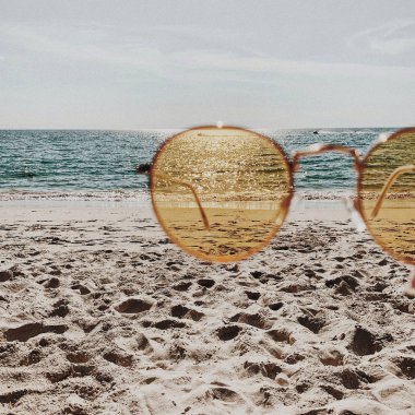 Beyaz kum, ayak adımları, mavi deniz ve sarı güneşli güneş gözlüğü ile tropikal güzel plaj. Yaz seyahati veya tatil konsepti. Minimalist arka plan.