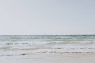 Phuket, Tayland dalgalar ile beyaz kum ve mavi deniz ile güzel tropikal plaj manzarası. Nötr renklerle minimal kompozisyon. Yaz konsepti. Doğal arka plan.