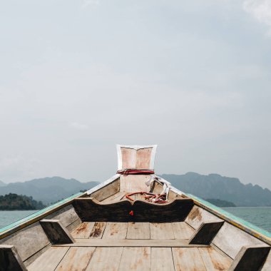 Cheow Lan Gölü, Khao Phang, Ban Ta Khun District, Tayland kayalar ve mavi göl ile tropikal adalar ile Egzotik ahşap tekne. Seyahat, tatil ve macera konsepti.