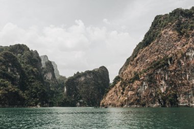 Cheow Lan Gölü, Khao Phang, Ban Ta Khun District, Tayland kayalar ve yeşil göl ile egzotik ve tropikal koyu yeşil ve kahverengi adalar. Seyahat tatil ve macera konsepti.