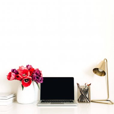 Dizüstü bilgisayar, lale çiçekleri buket, kırtasiye, lamba ile Ev ofis çalışma alanı arka plan. Kopya alanı şablonu ile Minimalist bayan patron blog kahraman başlık. Yaşam tarzı natürmort kavramı.