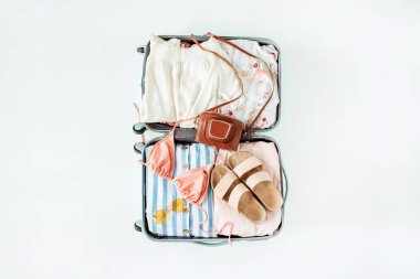 Bikini, güneş gözlüğü, terlik, retro kamera ve beyaz arka plan elbise ile el bagajı. Düz yatıyordu, üst görünüm seyahat tatil moda kompozisyon.