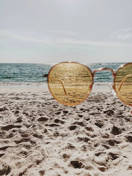 Beyaz kum, ayak adımları, mavi deniz ve sarı güneşli güneş gözlüğü ile tropikal güzel plaj. Yaz seyahati veya tatil konsepti. Minimalist arka plan.