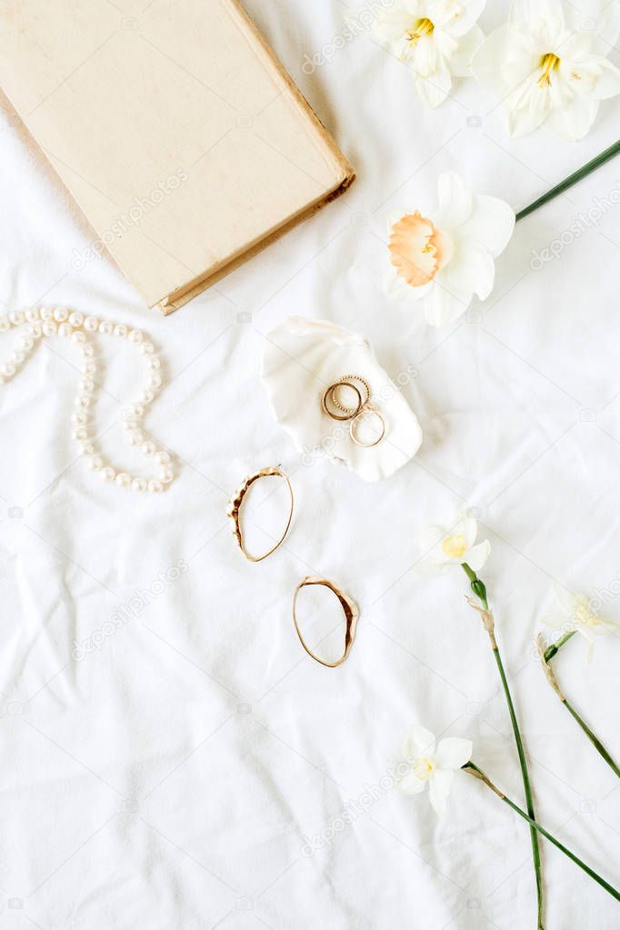 Minimal fashion French style composition with women's accessories: earrings, necklace, rings on white linen. Flat lay, top view.