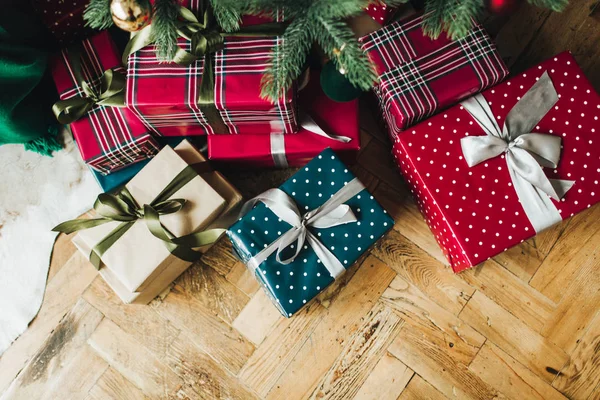 Noel / Yeni Yıl kompozisyonu. Noel ağacının altında kırmızı, mavi ve bej renkli kağıtlarla sarılı el yapımı kutular. Düz yerde, üst tarafta. Kış tatili kavramı.