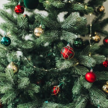 Noel / Yeni Yıl kompozisyonu. Kırmızı, altın, yeşil oyuncaklar, toplar ve çelenkle süslenmiş Noel ağacı. Kış tatili kavramı.