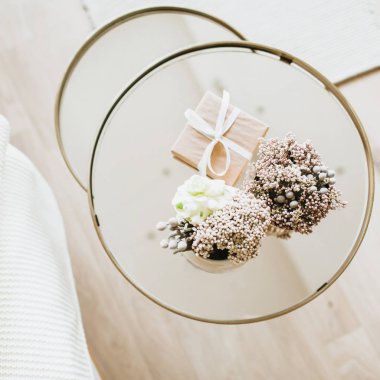 Ev bitkisi ve hediye paketi cam sehpanın üzerinde. Noel, yeni yıl, kış tatili geçmişi. Düz yatış, üst görünüm.