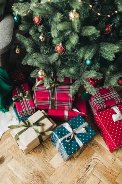 Noel / Yeni Yıl kompozisyonu. Noel ağacının altında kırmızı, mavi ve bej renkli kağıtlarla sarılı el yapımı kutular. Düz yerde, üst tarafta. Kış tatili kavramı.