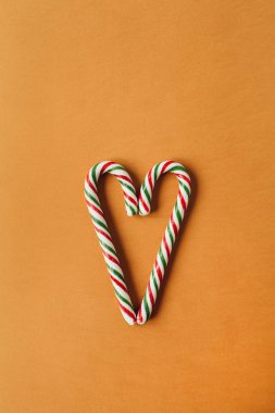 Zencefilli arka planda geleneksel çubuk şekerlerden yapılmış kalp sembolü. Düzlük, üst görünüm Noel / Yeni Yıl tatili konsepti.