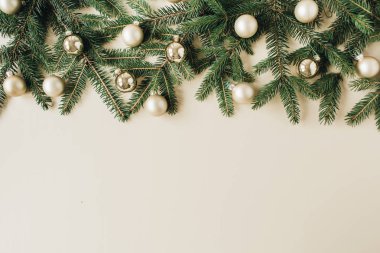 Noel / Yeni Yıl bayramı kompozisyonu. Firavun iğnesi dalları, bej arka planda noel süsleri. Düz yatar, üst görünüm, şenlik kahramanı başlığı.