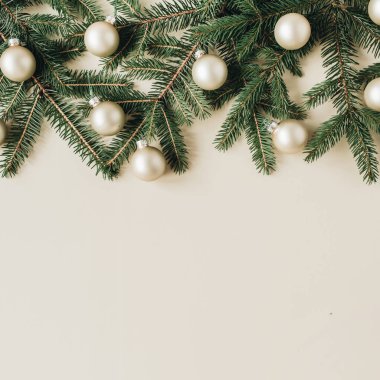 Noel / Yeni Yıl bayramı kompozisyonu. Firavun iğnesi dalları, bej arka planda noel süsleri. Düz yatar, üst görünüm, şenlik kahramanı başlığı.