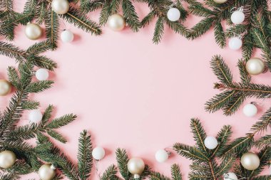 Noel / Yeni Yıl bayramı kompozisyonu. Köknar iğnelerinden ve pembe arka planda boş fotokopi alanı olan Noel süslemelerinden yapılmış çerçeve. Düz konum, üst manzara şenlik konsepti.