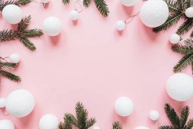 Noel / Yeni Yıl bayramı kompozisyonu. Çerçeveyi, köknar iğnesi dallarından yapılmış boş fotokopi alanı ve pembe arka planda noel süslemeleriyle donat. Düz konum, üst manzara şenlik konsepti.