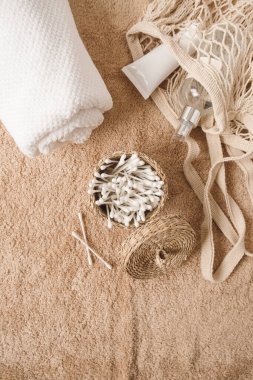 Güzellik, güzellik, spa, tedavi, havluyla sağlık kompozisyonu, kozmetik şişeler, sicim torbası, bej havluda kulak çubukları. Üst düzey hijyen, bakım kavramı.