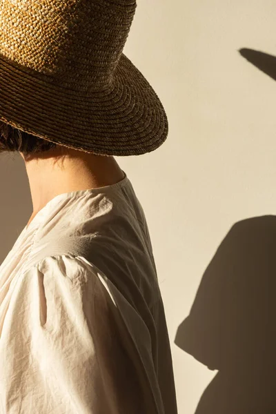 藁帽子の若いかなりの女性と壁に対する白いドレス サンドレス 壁に日光影 ミニマルファッションデザインのコンセプト — ストック写真