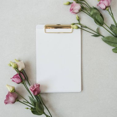 Boş fotokopi alanı olan boş bir kağıt tabaka, güllerden oluşan bir çerçeve. Düz konum ve üst görünüm işi şablon arkaplanı oluşturur