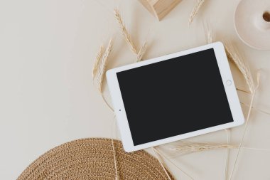 Buğday / çavdar sapları ve bej arkaplanlı hasır peçeteli tablet. Düz konum, üst görünüm modelleme alanı şablonu