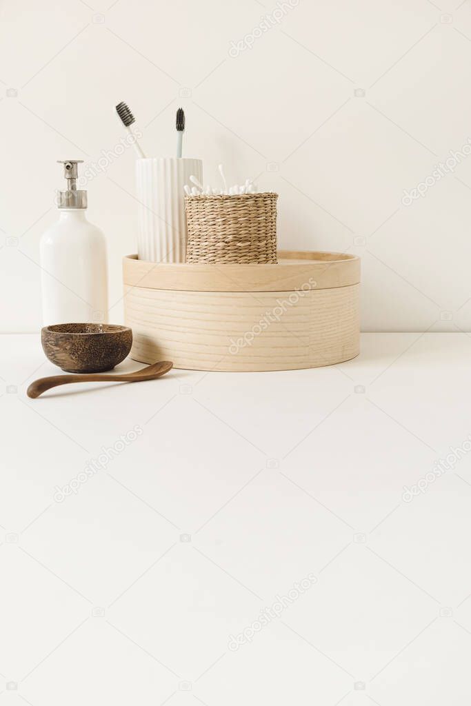 Beauty health care composition with ear sticks in rattan casket, powder, toothbrushes, liquid soap on white table. Women's beauty treatment routine concept