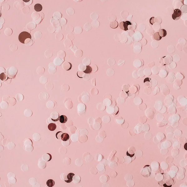 Pink celebration background with holiday sparkling confetti. Flat lay, top view