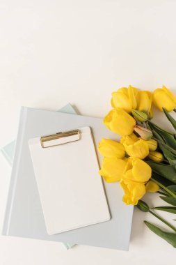 Güzel modern ofis çalışma alanı. Panosu, kırtasiyesi ve lale çiçekleri var. Flatlay, üst düzey minimalist çalışma masası. Taklit alanı olan boş sayfa kağıdı