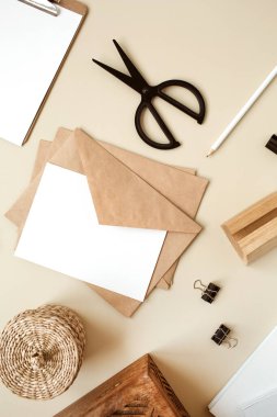 Bej masasında zarflı boş kağıt. Sanatçının çalışma masası ahşap tabut, kalem ve kırtasiye malzemesi. Ağlı davetiye kartı. Düz yatış, boş kopyalama alanı olan üst görünüm modeli