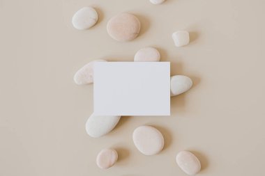 Fotokopi alanı ve bej arkaplanda taşlar olan boş kağıt kağıtlar. Minimal ticari marka şablonu. Düz yatış, üst görünüm.