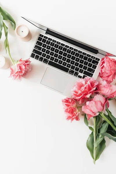 Laptop and beautiful pink peony tulip flowers on white background. Flat lay, top view minimalist home office desk workspace with blank copy space