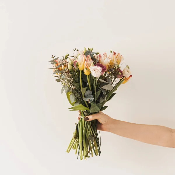 Mano Femenina Sosteniendo Flores Tulipán Ramo Contra Pared Blanca Celebración — Foto de Stock