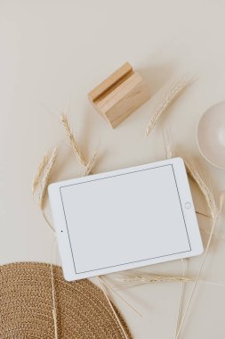 Buğday / çavdar sapları ve bej arkaplanlı hasır peçeteli tablet. Düz konum, üst görünüm modelleme alanı şablonu