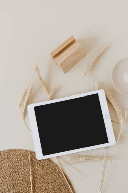Buğday / çavdar sapları ve bej arkaplanlı hasır peçeteli tablet. Düz konum, üst görünüm modelleme alanı şablonu