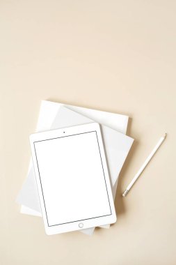 Tarafsız bej arka planda boş dokunmatik ekranlı tablet. Düz konum, üst görünüm, kopyalama alanı olan boş maket. Serbest yazar, blogcu, web tasarımcısı, minimalist ofis çalışma alanı