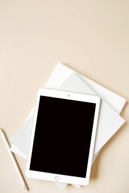 Tarafsız bej arka planda boş dokunmatik ekranlı tablet. Düz konum, üst görünüm, kopyalama alanı olan boş maket. Serbest yazar, blogcu, web tasarımcısı, minimalist ofis çalışma alanı