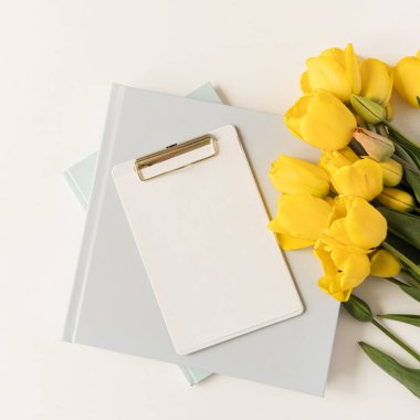 Güzel modern ofis çalışma alanı. Panosu, kırtasiyesi ve lale çiçekleri var. Flatlay, üst düzey minimalist çalışma masası. Taklit alanı olan boş sayfa kağıdı