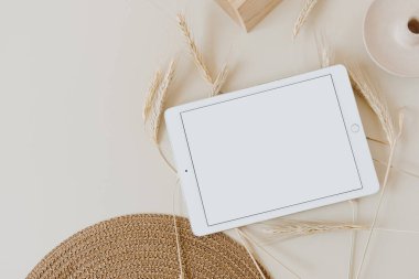 Buğday / çavdar sapları ve bej arkaplanlı hasır peçeteli tablet. Düz konum, üst görünüm modelleme alanı şablonu