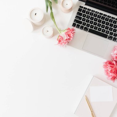 Laptop ve güzel pembe şakayık lale çiçekleri, boş kağıt kağıtlar, beyaz arka planda mumlar. Düz konum, üst görünüm minimalist ofis ofis çalışma alanı boş kopya alanı